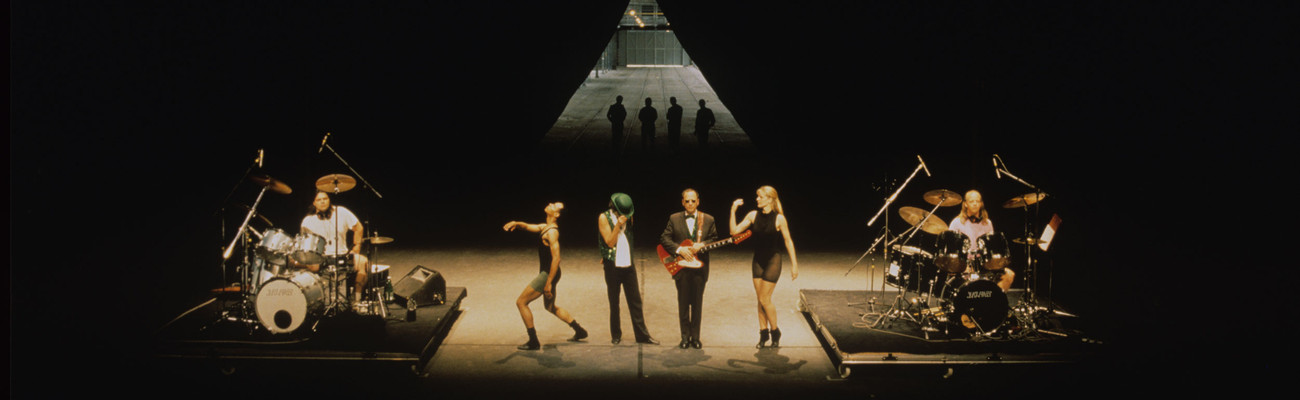 Mike Kelley, Anita Pace, Stephen Prina. Beat of the Traps. 1992. Performed in Expanded Art, Wiener Festwochen, The Remise, Vienna, Austria, 1992. Performers (from left): Jonathan “Butch” Norton, Carl Burkley, Alan Abelew, Stephen Prina, Anita Pace, M.B. Gordy. Photo: Karl Krauss. © Mike Kelley Foundation for the Arts. All Rights Reserved/VAGA at ARS, NY.⁠, Anita Pace, Stephen Prina