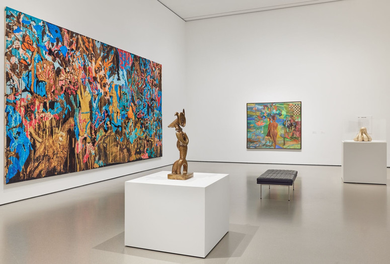 Installation view of Gallery 215: Jungle Jungle, The Museum of Modern Art, New York, May 2, 2025–ongoing. Photo: Martin Parsekian. Image description: a photograph of a gallery installed with colorful large-scale paintings on the wall and bronze sculptures on white pedestals, with a black gallery bench in the center