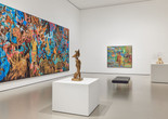 Credit: Installation view of the gallery Jungle Jungle, The Museum of Modern Art, New York, May 2, 2025–ongoing. Photo: Martin Parsekian. Image description: A photograph of a gallery installed with colorful large-scale paintings on the wall and bronze sculptures on white pedestals, with a black gallery bench in the center