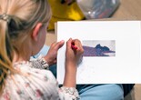 A child adds marks to an activity sheet that shows a pointillist painting. Photo: On White Wall, Inc.