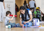 A child and an adult build a paper sculpture in the galleries during UNIQLO Family Day. Photo: On White Wall, Inc.
