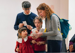 A group of people are looking intently at papers in their hands. The photo features predominant colors of red and blue. Photo: On White Wall, Inc.