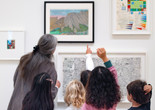 An educator and group of kids look closely at an artwork together. Photo: On White Wall, Inc.