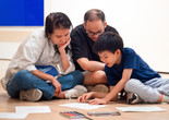A child and two adults do a drawing activity on the floor during Family Art Adventures in Mandarin. Photo: On White Wall, Inc.