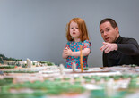 An adult points to the Broadacre City architectural model by Frank Lloyd Wright as their child looks on. Photo: On White Wall, Inc.