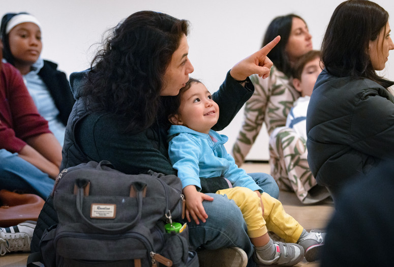 An adult points to an artwork as their child looks on during Arte en Familia. Photo: On White Wall, Inc.