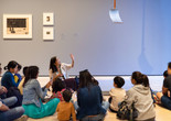 An educator leads a conversation to a group of young children and their families in front of a sculpture. Photo: On White Wall Inc.