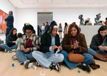 A parent and two teens sit on the floor of the galleries and make small sculptures using model magic. Photo: On White Wall, Inc.