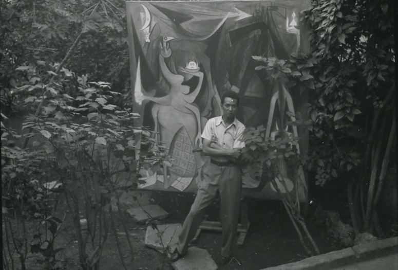 Wifredo Lam with the unfinished Bélial, empereur des mouches (Belial, Emperor of the Flies, 1948) in his garden, Havana, 1947. Archives SDO Wifredo Lam, Paris. Photograph by Ylla © Pryor Dodge
