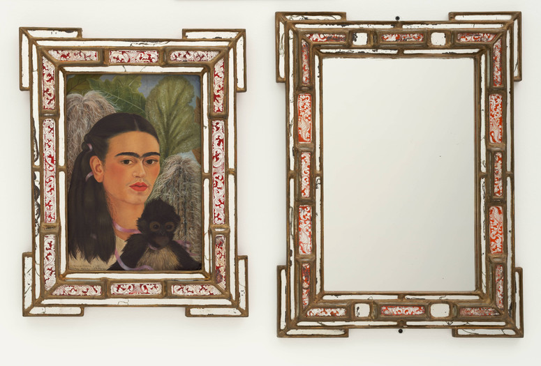 Frida Kahlo. Fulang-Chang and I. 1937 (assembled after 1939). In two parts, oil on board (1937) with painted mirror frame (added after 1939); and mirror with painted mirror frame (after 1939). The Museum of Modern Art, New York. Mary Sklar Bequest. © 2026 Banco de México Diego Rivera Frida Kahlo Museums Trust, Mexico, D.F./Artists Rights Society (ARS), New York. Image description: A diptych featuring two rectangular, brass-colored frames with red and white decorative glass inserts. The frame on the left holds a self-portrait of Frida Kahlo with a small dark monkey resting on her chest, while the frame on the right holds a mirror.