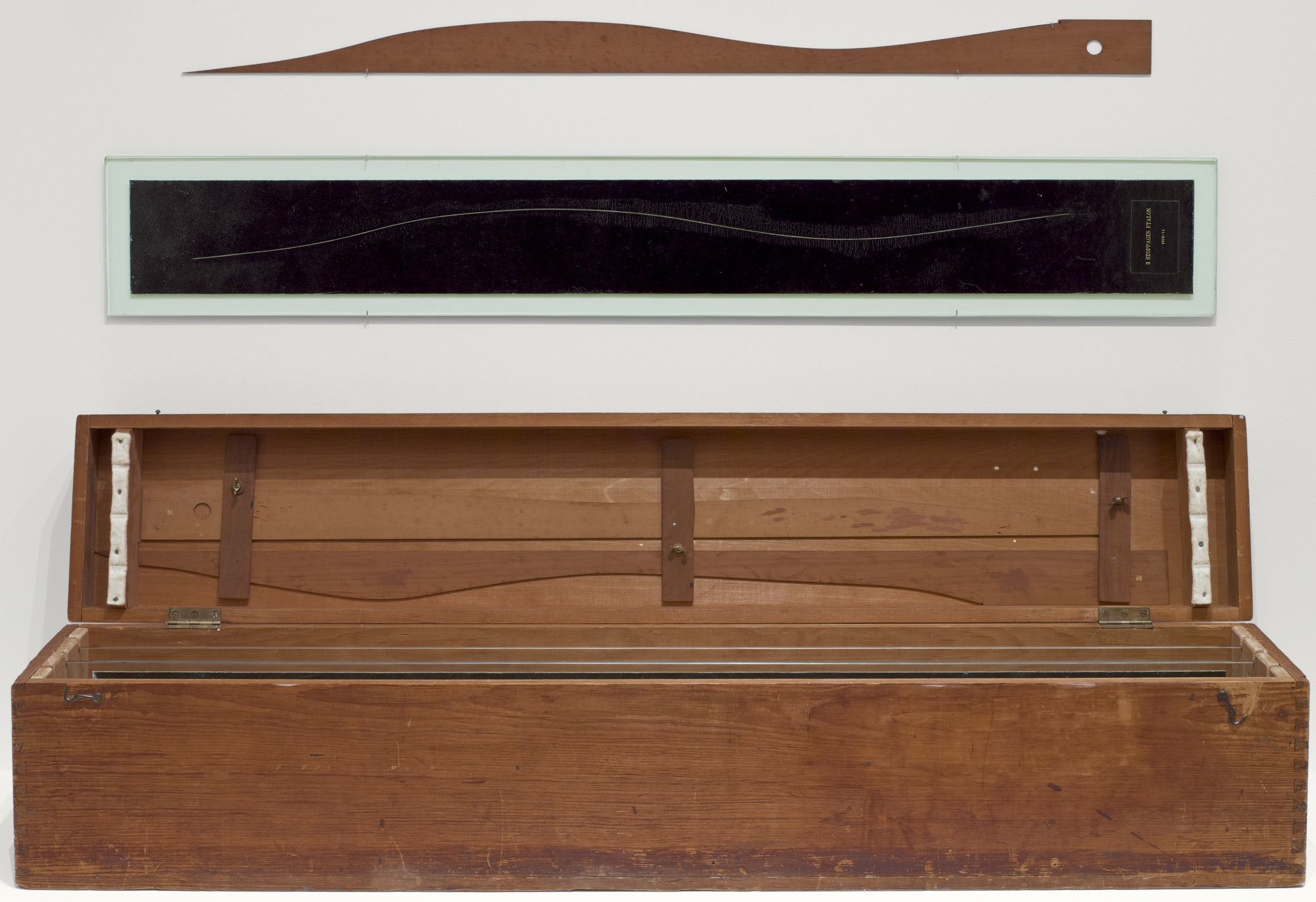 Marcel Duchamp. *3 Standard Stoppages*. 1913–14. Wood box 11 1/8 x 50 7/8 x 9" (28.2 x 129.2 x 22.7 cm), with three threads 39 3/8" (100 cm), glued to three painted canvas strips 5 1/4 x 47 1/4" (13.3 x 120 cm), each mounted on a glass panel 7 1/4 x 49 3/8 x 1/4" (18.4 x 125.4 x 0.6 cm), three wood slats 2 1/2 x 43 x 1/8" (6.2 x 109.2 x 0.2 cm), shaped along one edge to match the curves of the threads. The Museum of Modern Art, New York. Katherine S. Dreier Bequest. © 2026 Artists Rights Society (ARS), New York / ADAGP, Paris / Estate of Marcel Duchamp