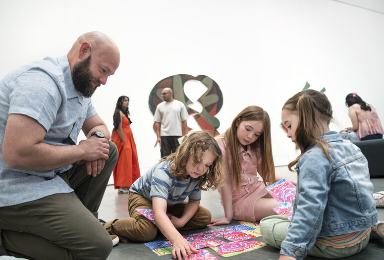 An adult and three children put together a colorful puzzle on the floor during a UNIQLO Family Day. Photo: Martin Seck