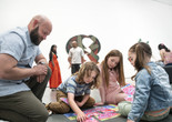 An adult and three children put together a colorful puzzle on the floor during a UNIQLO Family Day. Photo: Martin Seck