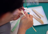 A child works on sculpting an animal out of white air-dry clay and tan-colored clay tools. Photo: On White Wall, Inc.