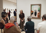 An educator speaks with a group of participants in front of a painting during Meet Me at MoMA. Photo: Jason Lindberg