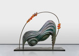 Camille Henrot. 73 / 37 (Abacus). 2024. Bronze, resin, rubber, and Japanese pigments. The Museum of Modern Art, New York. Gift of Sarah Arison Image description: A large bronze sculpture featuring smooth, flowing forms, like ripples in sand. It stands on two legs at each end atop a flat rectangular platform. Two round lumps sit on the underside of the sculpture. A thin metal arch circles above, with 10 large orange glass beads strung along it.