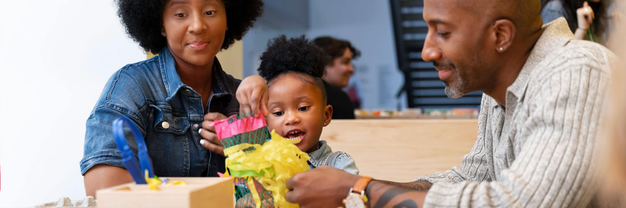 Parents and a child use recycled materials to create a creature in Art Lab. Photo: Martin Seck