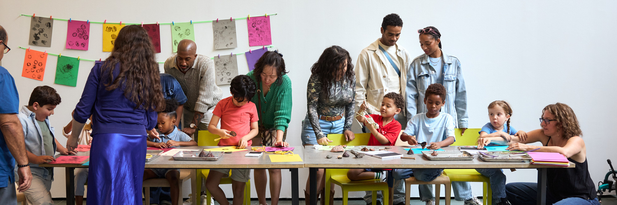Families work together to make prints at a table while an educator assists. Photo: Alycia Kravitz