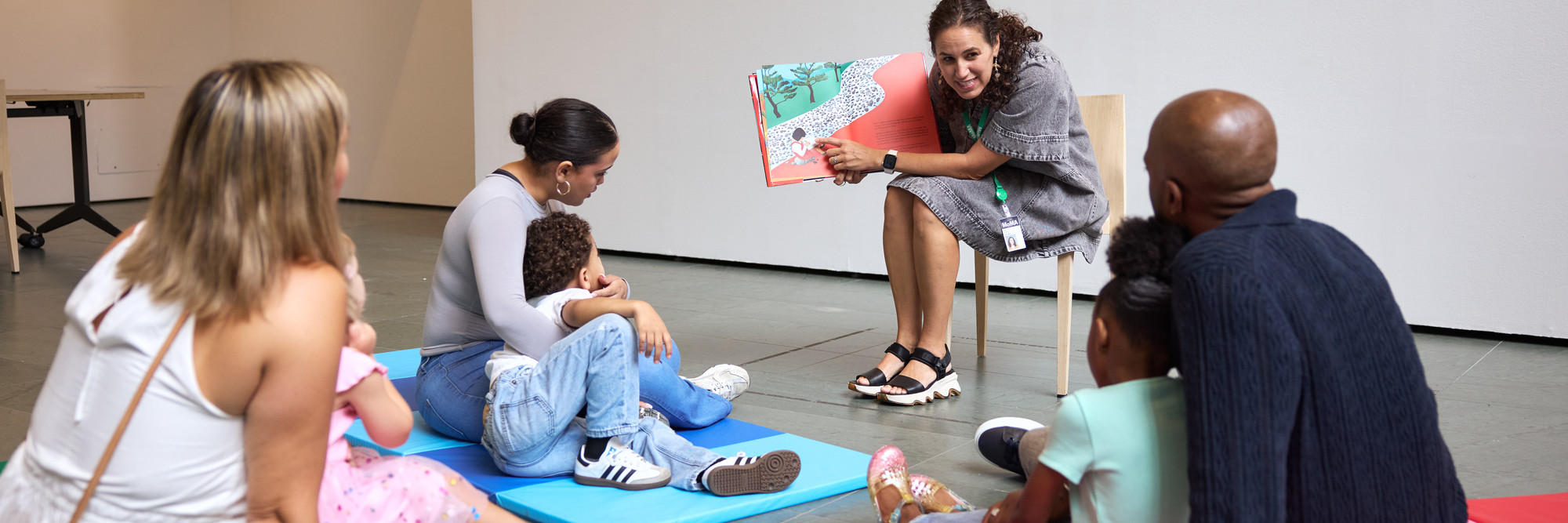 Photo: Alycia KravitzImage: An educator reads a story while families sit together and look at the book.