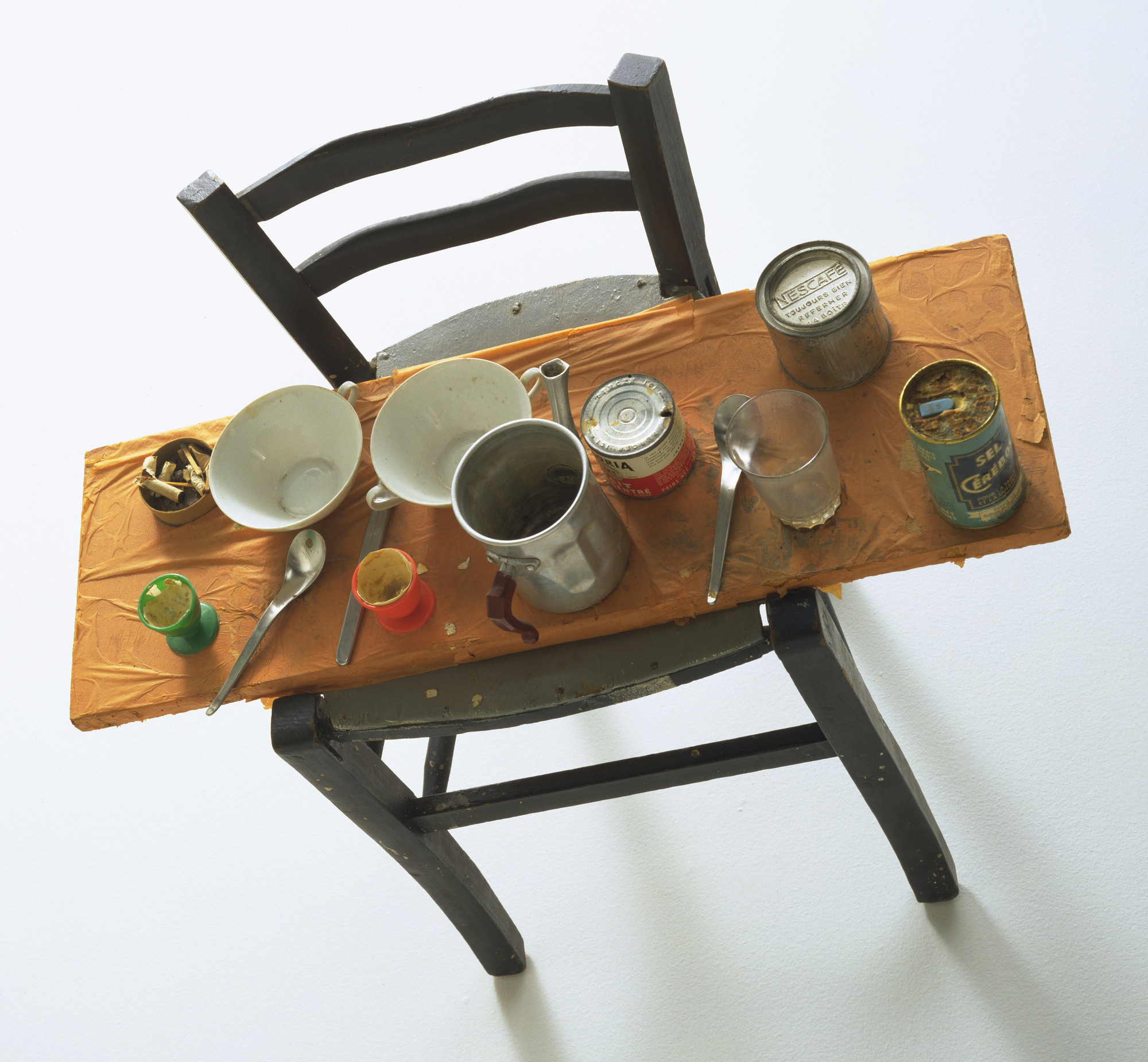 Daniel Spoerri. Kichka’s Breakfast I 1960. Wood chair hung on wall with board across seat, coffeepot, tumbler, china, eggcups, eggshells, cigarette butts, spoons, tin cans, and other materials. Philip Johnson Fund.