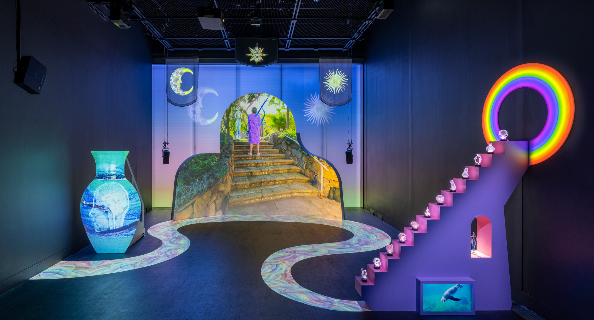 Shana Moulton. Meta/Physical Therapy. 2023–24. Eight-channel 4K and high-definition video (color, sound; 14:49 min.), MDF, vinyl, seating, scrims, props, and window gel, dimensions variable. Courtesy the artist, Galerie Crèvecœur, and Galerie Gregor Staiger. ©️2024 Shana Moulton. Installation view, The Museum of Modern Art, New York, February 17–April 21, 2024. Photo: Jonathan Dorado