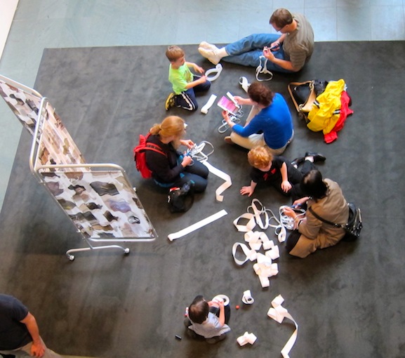 Visitors trying Lygia Clark's proposition, Caminhando on the rug at MoMA Studio: Breathe with Me with Allison Smith's Joining Screens project as a backdrop. Photo by Sarah Kennedy