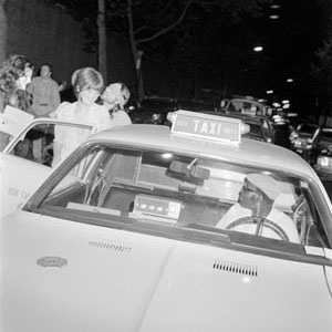Photo of a blindfolded person standing next to a taxi