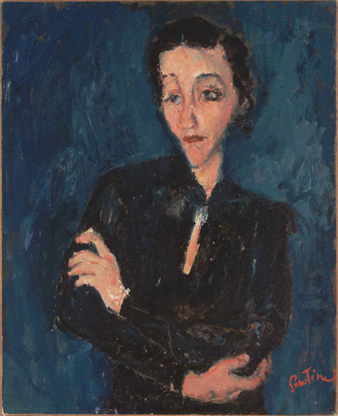 A person with peachy pink skin, black eyebrows and hair and a somber expression, wearing dark clothing cradling their arms. The figures is set against a blue background with visible brushstrokes. The lower right corner features a red signature ofthe artist &#34;Soutine.&#34; This is an AI generated description. To give feedback, email ai@moma.org.