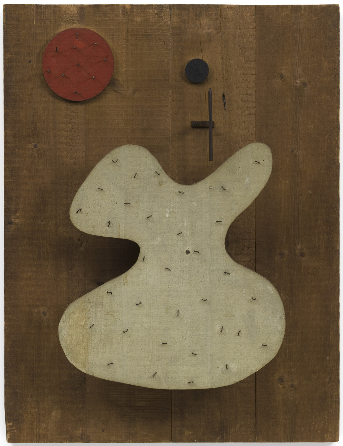 A wooden panel with a beige, kidney-shaped object with nails embedded in it. Above it, a red circle and a black circle with a horizontal and vertical line are attached. This is an AI generated description. To give feedback, email ai@moma.org.