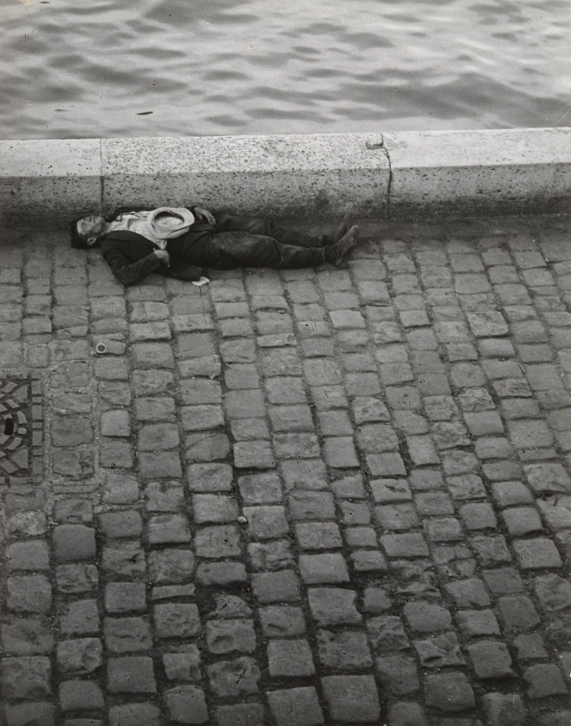 Brassaï (Gyula Halász). Man Sleeping Along the Seine. (Homme endormi au bord de la Seine). 1932