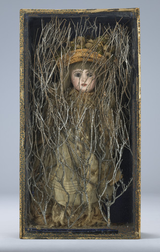 A doll with a porcelain face and blonde hair, dressed in brown and beige clothing, is encased in a box with intertwined silver branches obscuring its figure. The box has a worn, decorated edge. This is an AI generated description. To give feedback, email ai@moma.org.