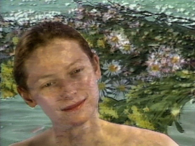 A person&#39;s face with a gentle expression is seen against a background of green foliage and white daisies. The predominant colors are green and white with some yellow accents. This is an AI generated description. To give feedback, email ai@moma.org.