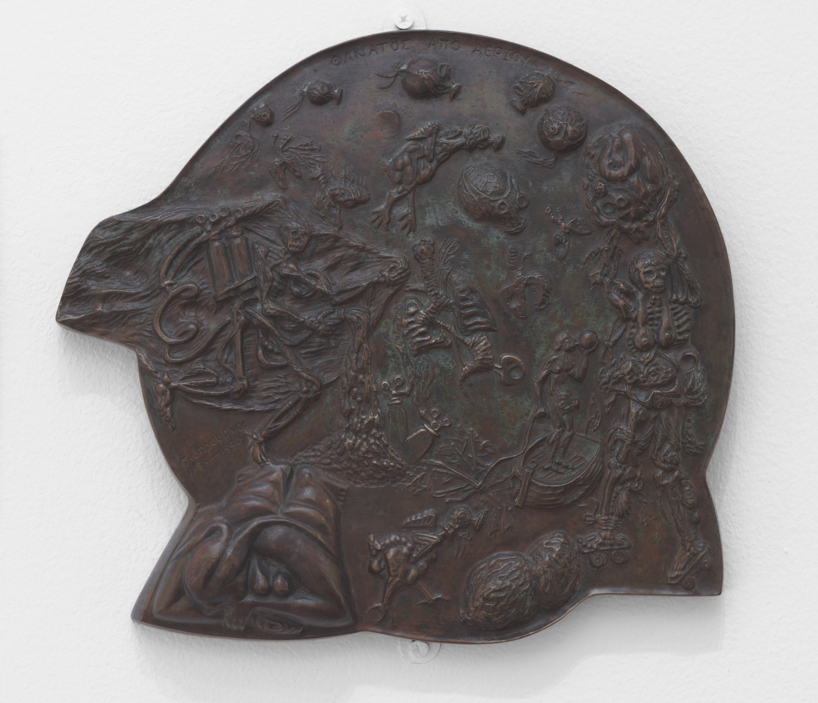 A dark bronze-colored relief sculpture features numerous detailed figures in various poses, including skeletal forms and organic shapes, all incorporated into an irregularly shaped base. The background exhibits textural elements and intricate carvings. This is an AI generated description. To give feedback, email ai@moma.org.