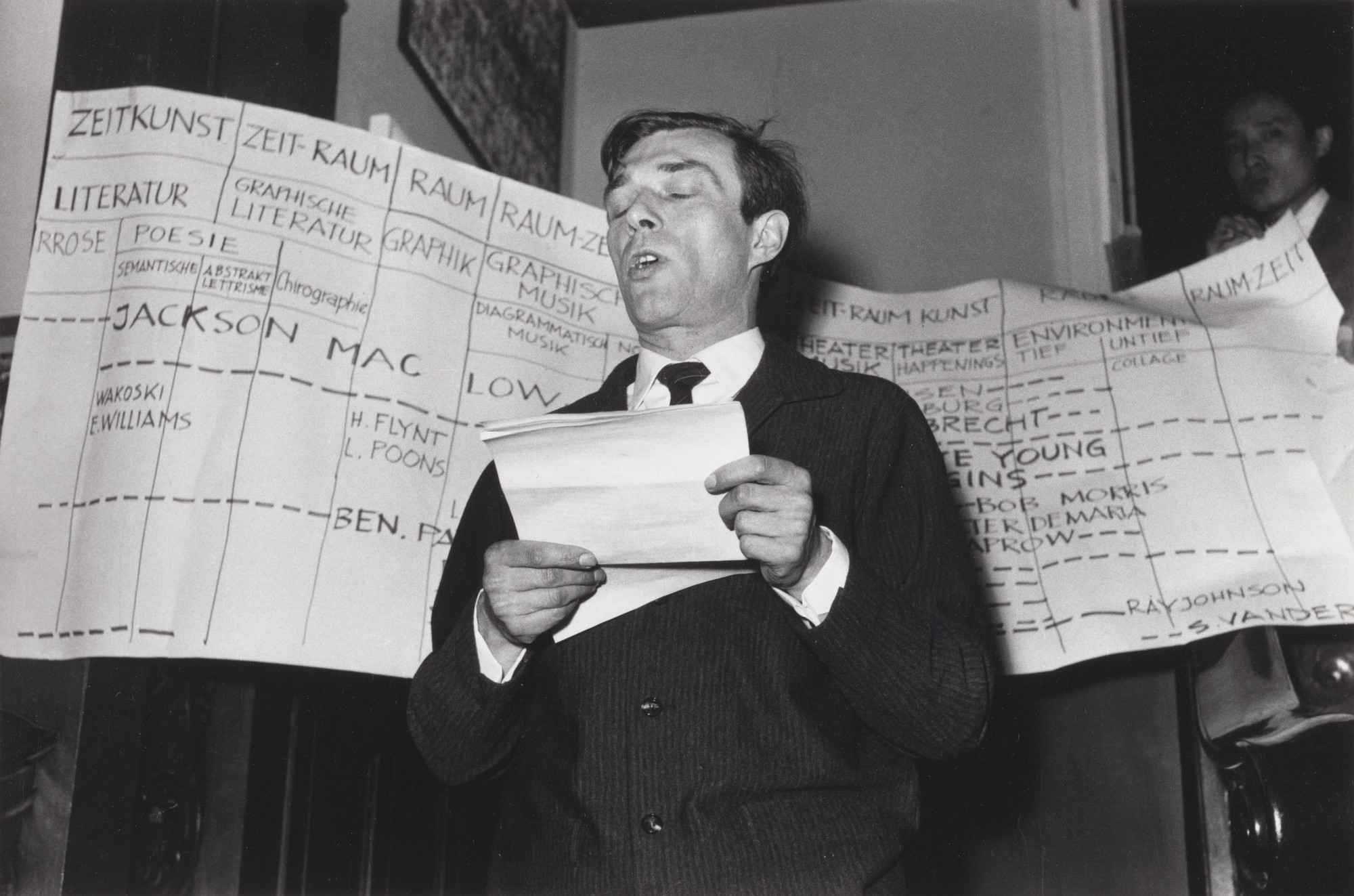 Unidentified photographer, George Maciunas, Arthus Carlheinz Caspari. Arthus C. Caspari reading George Maciunas&#39; manifesto Neo-Dada in Music, Theater, Poetry, Art, during Kleines Sommerfest: Après John Cage, Galerie Parnass, Wuppertal, West Germany, June 9, 1962. 1962