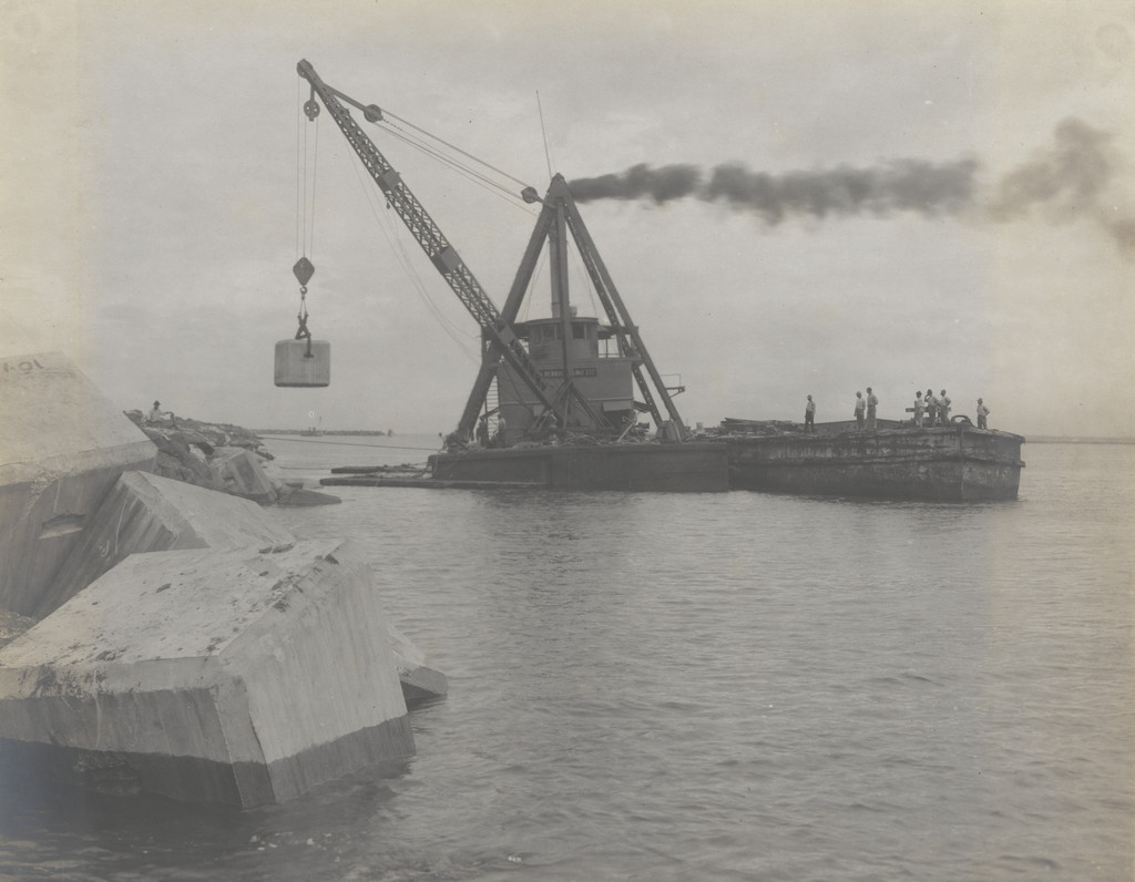 Toro Point Breakwater. Derrick barge placing 25-ton concrete blocks on bay slope