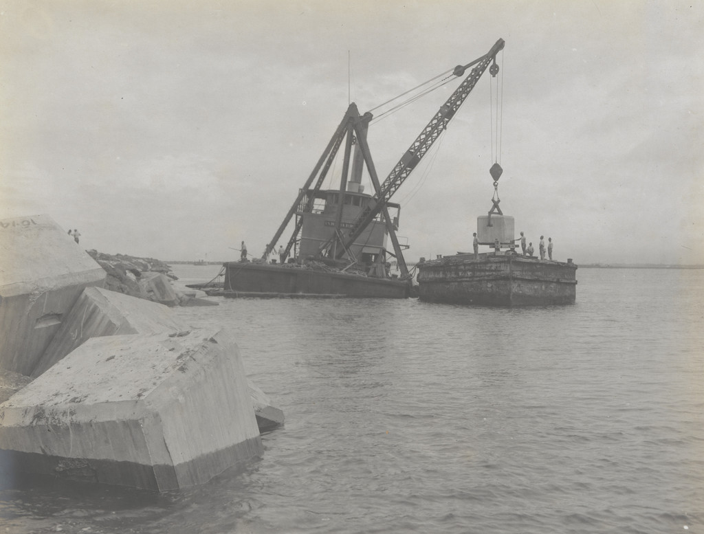 Toro Point Breakwater. Derrick barge placing 25-ton concrete blocks on bay slope
