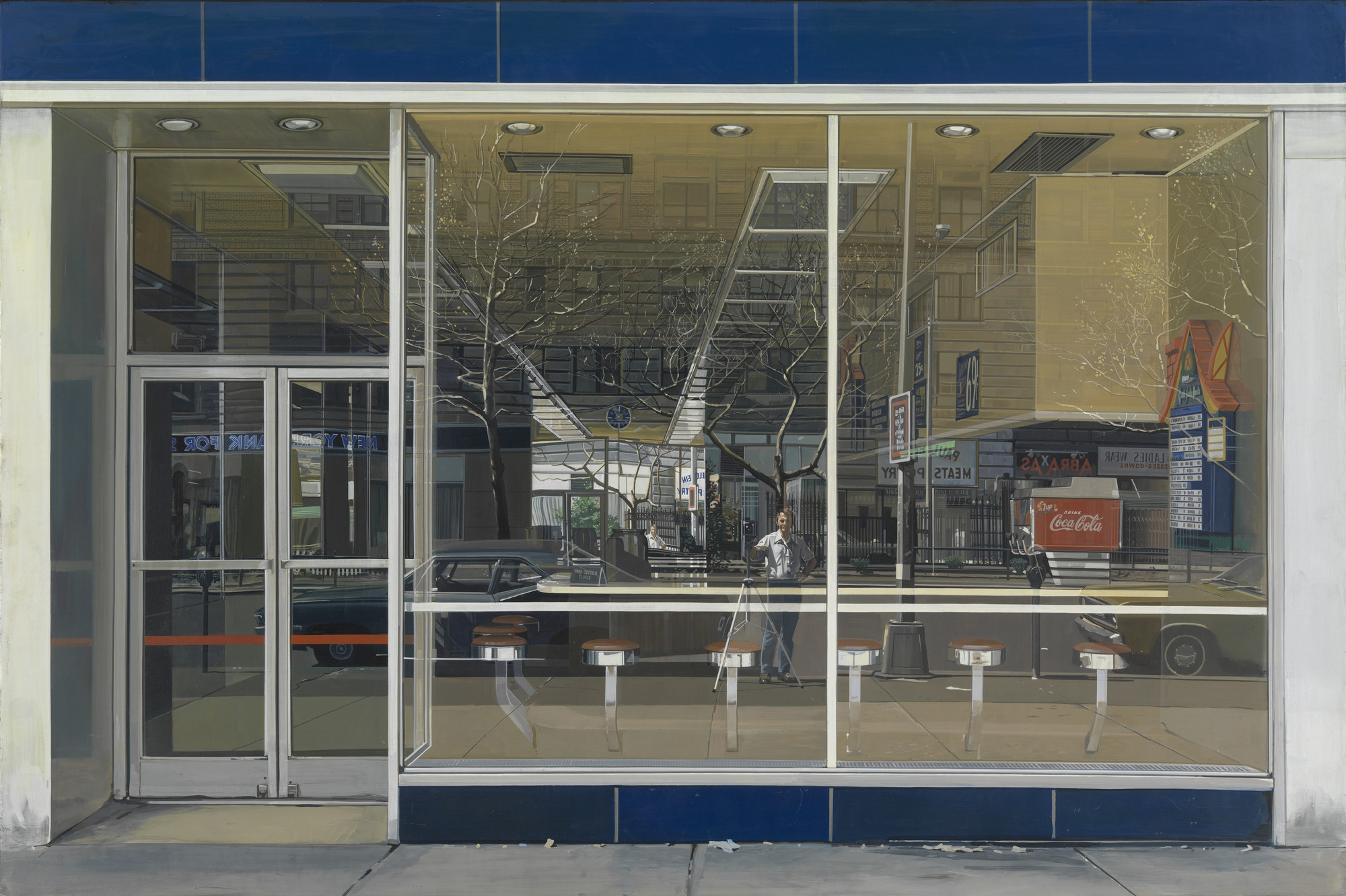 A large, reflective glass window shows a street scene with buildings, a person, and trees seen through and reflected on it. Predominantly blue, brown, and grey colors are used in the image. This is an AI generated description. To give feedback, email ai@moma.org.