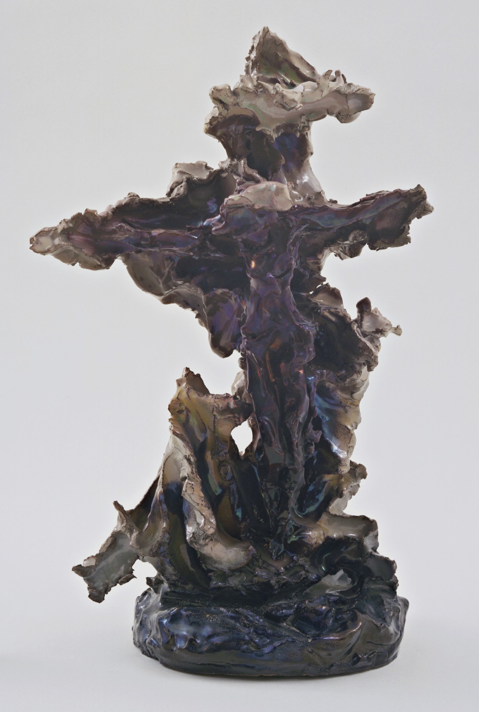 A twisted sculpture with a rough, uneven surface in predominant dark purples and blues, stands on a round base. The form is irregular and jagged, against a plain white background. This is an AI generated description. To give feedback, email ai@moma.org.