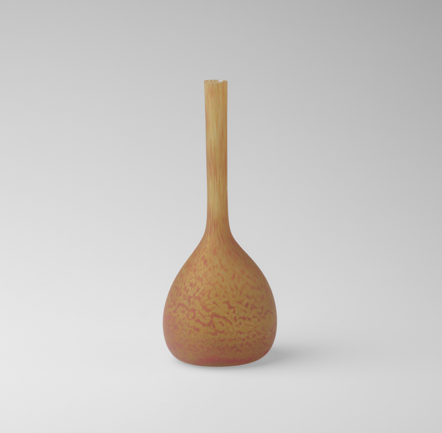 A vase with a round bottom and a long narrow neck is predominantly orange with red speckles. The background is light gray. This is an AI generated description. To give feedback, email ai@moma.org.