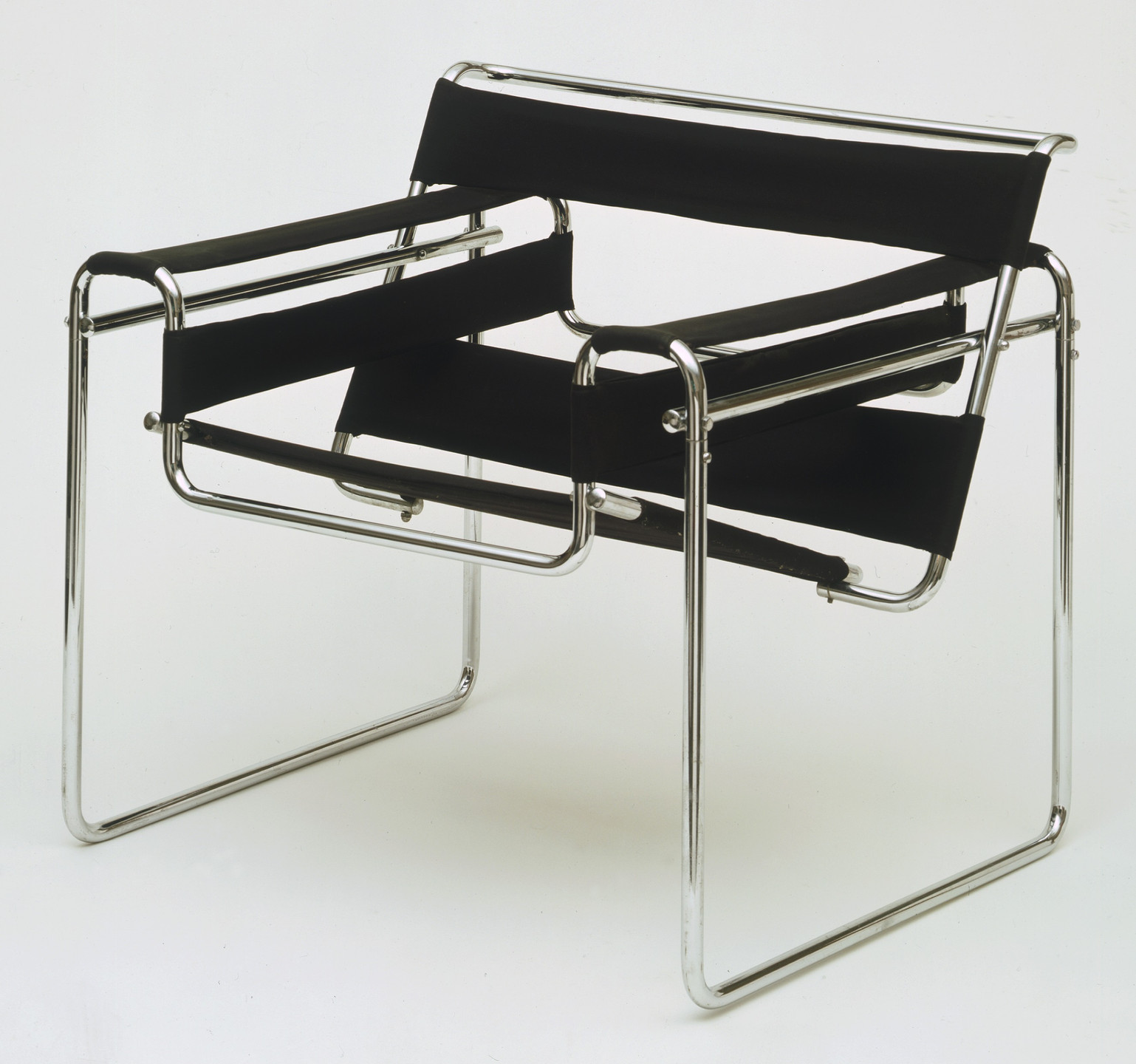 A sleek chair with a shiny metal frame, featuring black, wide fabric strips for the backrest, seat, and armrests. The chair has a minimalist design with a cantilevered base. This is an AI generated description. To give feedback, email ai@moma.org.