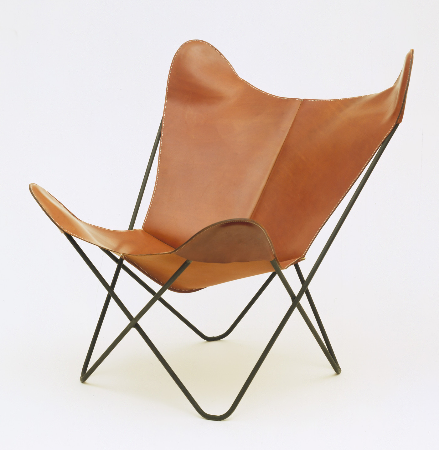 A brown leather chair with a reclined back and butterfly shape. It is supported by a black metal frame and the legs form an X shape. This is an AI generated description. To give feedback, email ai@moma.org.