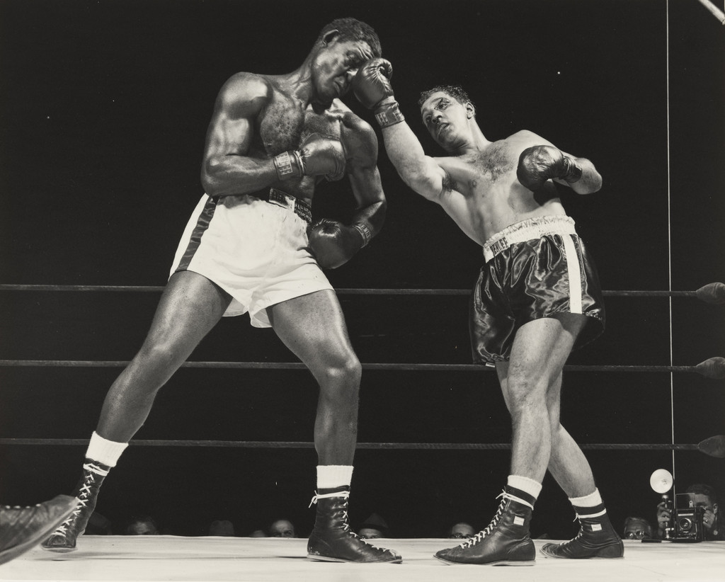 Champion Rocky Marciano, his eye cut, flattens challenger Ezzard Charles' nose with crushing right uppercut in sixth at stadium