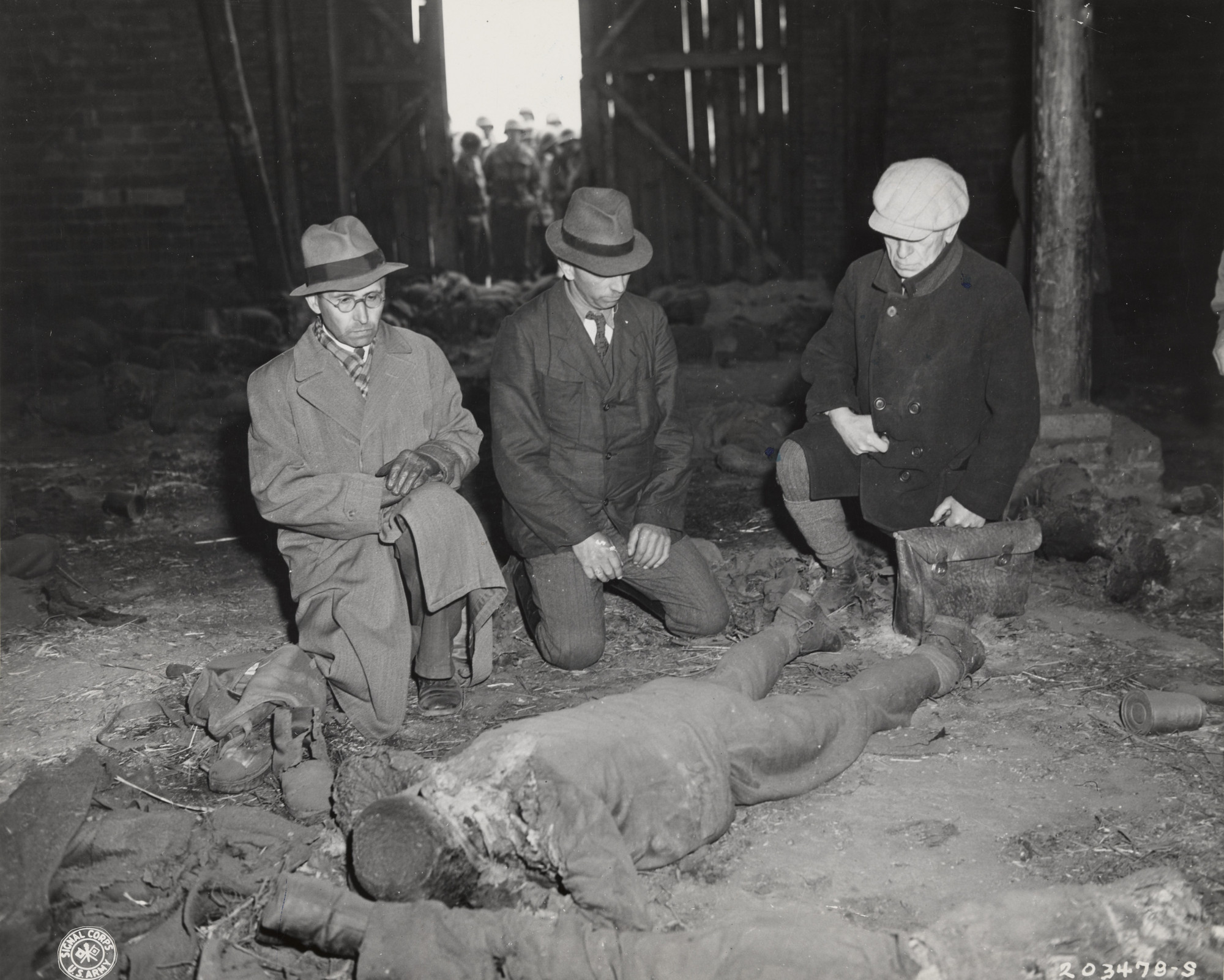 U.S. Army Signal Corps. "Three Germans Examine a Mass Execution Victim at Gardelegen"