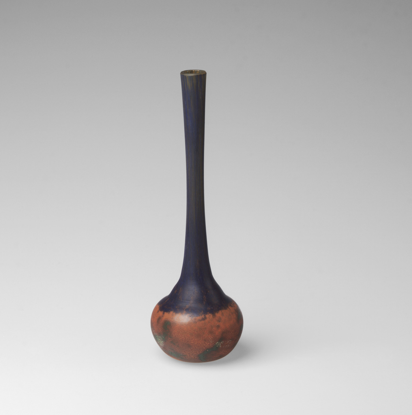 A slender vase with a long, narrow neck widening into a round base. The vase&#39;s neck is predominantly blue, while the base blends blue with reddish-brown tones and hints of green. This is an AI generated description. To give feedback, email ai@moma.org.