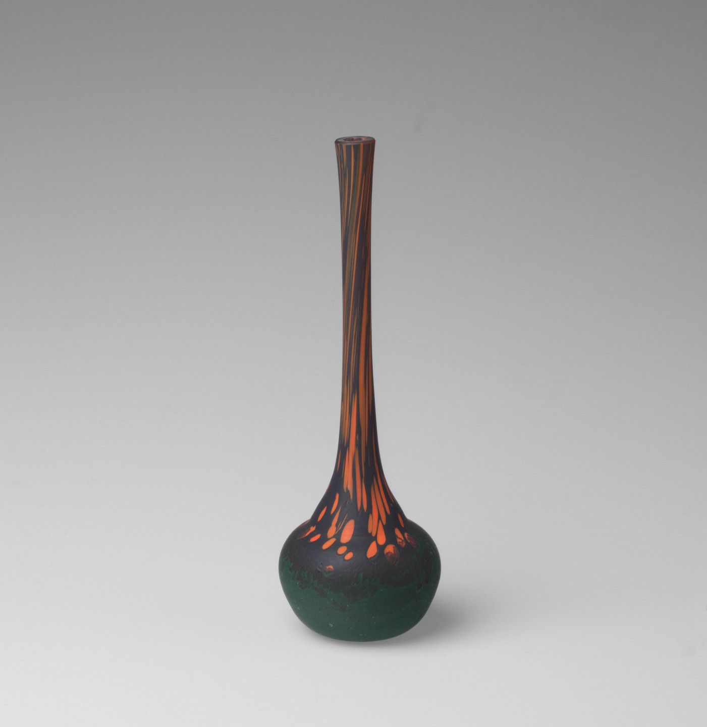 A tall, slender vase with a round base, featuring dark green, blue, and orange colors. The neck of the vase has vertical orange streaks, transitioning to a predominantly dark green base. This is an AI generated description. To give feedback, email ai@moma.org.