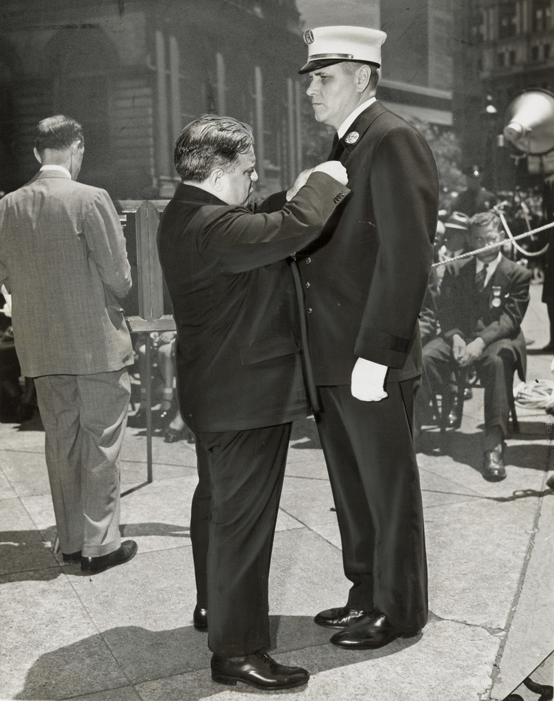 "Fire Captain John W Heany Receiving the James Gordon Benefit and Department Medals from Mayor LaGuardia"