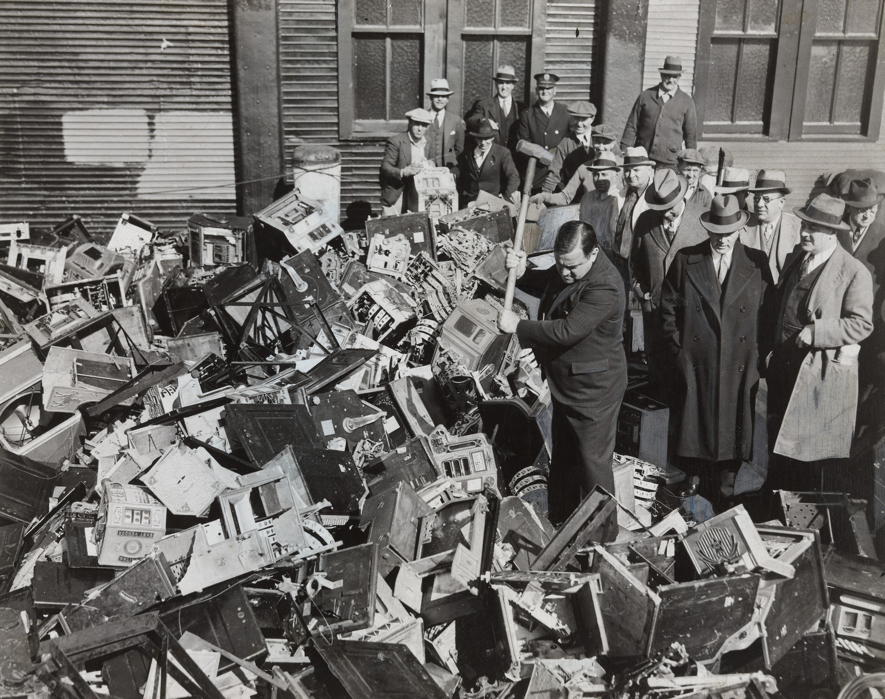 Times Wide World Photos. Mayor La Guardia Giving the Axe to Slot Machines Which Were Dumped in Waters off Scotland Light. October 13, 1934
