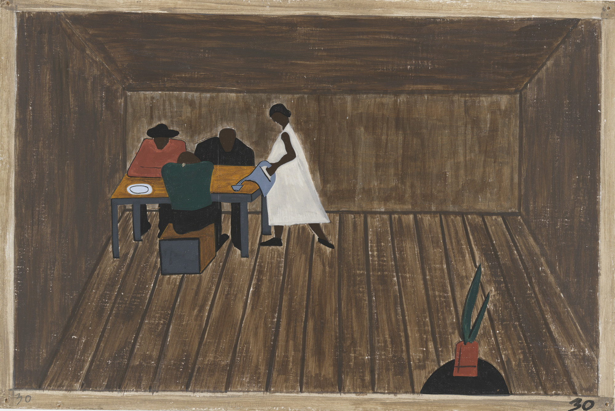 Three people sit at a wooden table in a brown room, with a fourth person in a white outfit standing nearby. A small potted plant is in the bottom right corner on the wooden floor. This is an AI generated description. To give feedback, email ai@moma.org.