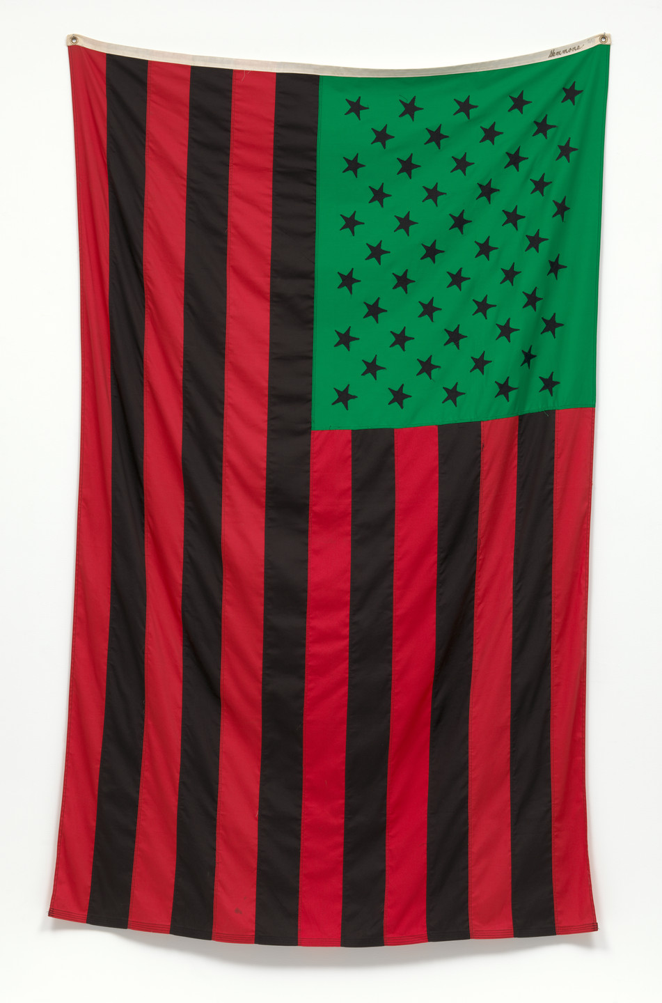 The image shows a flag with alternating red and black vertical stripes. The top left corner has a green square with black stars. This is an AI generated description. To give feedback, email ai@moma.org.