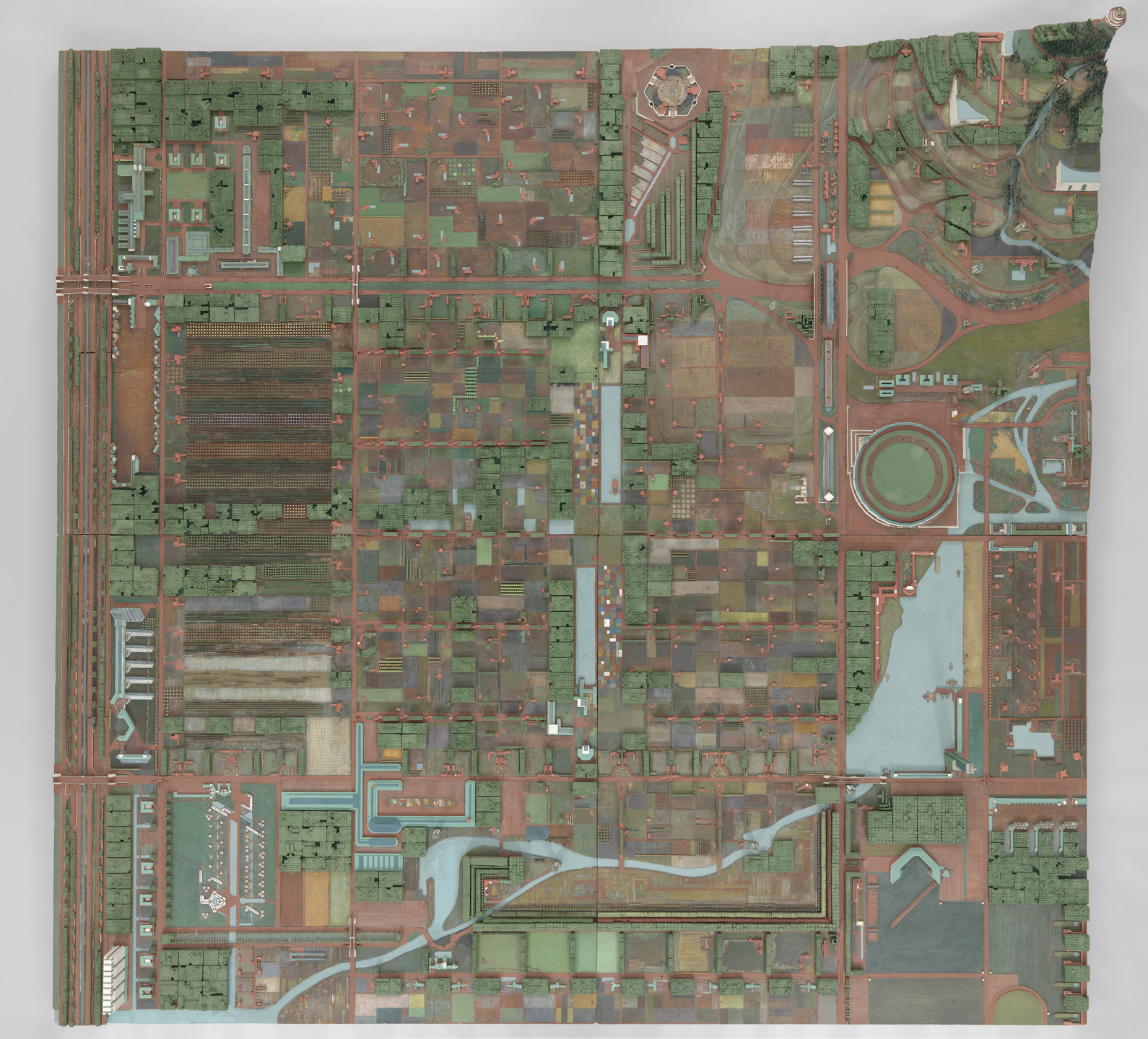 The image displays an aerial view of a detailed grid-like city layout with numerous rectangular and square sections in green, brown, and blue tones. Notable features include a circular area and winding blue pathways. This is an AI generated description. To give feedback, email ai@moma.org.